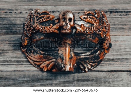 Copper steampunk mask with a skull on the background of a wooden table. Venetian masquerade mask for the festival. Mardi Gras.