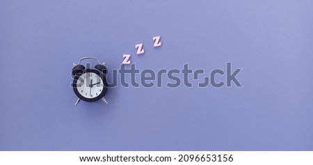 The banner is very peri. The concept of sleep. Black Alarm Clock on purple background