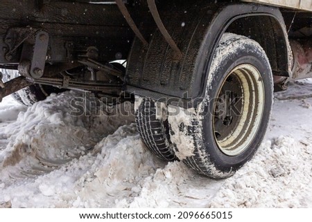 Dirty truck wheel stuck in a snowy road