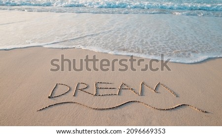 
the inscription "DREAM" on the sand of the coastline.