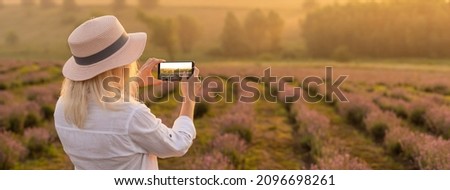 The hand of the person taking the picture of flowers on the smartphone