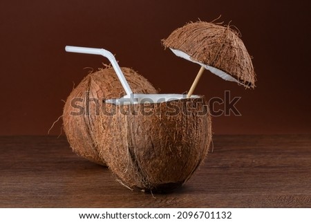 Coconut cocktail with a straw on brown background
