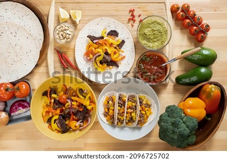 Flat layout of fresh fruit, vegetables and other ingredients for cooking mexican taco on wooden kitchen table