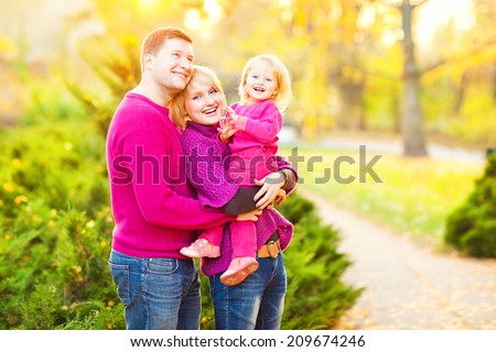 Picture of lovely family in autumn park, young parents with nice adorable kid playing outdoors. Picnic in the autumn park.