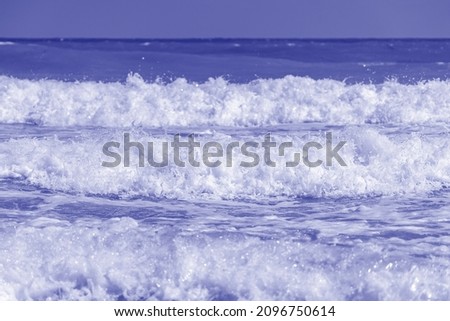 White sea waves on the tropical beach, close up. Trendy color of the year 2022 . Ultra Violet creative and moody color of the picture