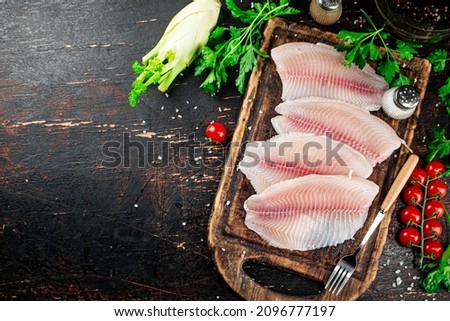 Raw fish fillet with tomatoes and herbs. Against a dark background. High quality photo