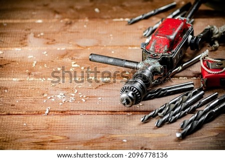 Drill with drills on the table. On a wooden background. High quality photo