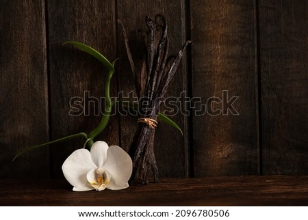 Vanilla green leaves ,dried pods on an old wood background.