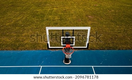 Vibrant blue basketball hoop at public park with autumn grass background. 