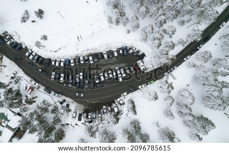 Drone aerial of a car parking on the snowy forest mountain in winter. Troodos mountains Cyprus wintertime season