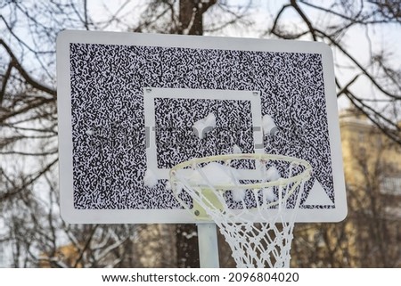 The basketball basket and backboard are stylized as a modern QR code. Photographed in the daytime in a winter snow-covered park