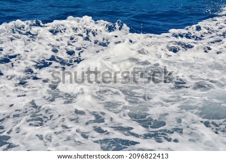 Foam of the sea. Rough deep turquoise and blue sea with white foam bubbles texture background. 