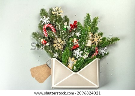 Christmas festive composition with fir tree branches, New Year toys, snowflakes, and traditional decoration. Envelope, gray background, creative flat lay, top view