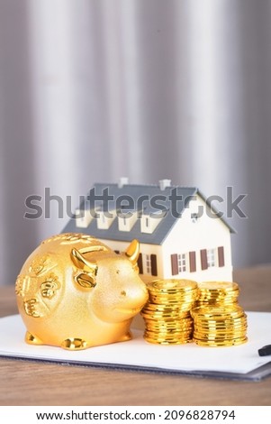 Taurus piggy bank and gold coins and house model on file.The Chinese character in the picture means "Lucky Strike"