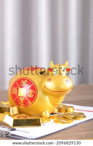 The Taurus piggy bank is surrounded by a pile of gold bars and coins on the file. The Chinese character in the picture means: "Lucky Strike"