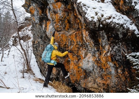 The traveler climbing mountain in winter.Snowy forest and rocks. Stick, cane for support. Survival in the wild. High quality photo