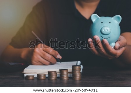 Woman hand holding piggy bank on wood table, saving money wealth and financial concept, Business, finance, investment, Financial planning,vintage picture style concept.
