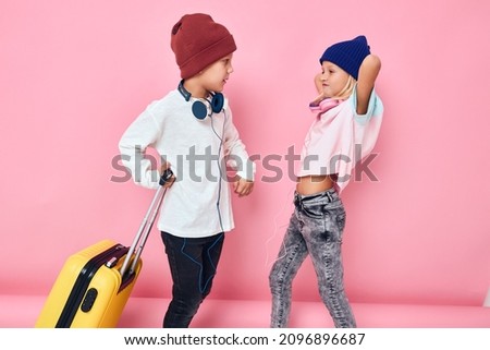 Portrait of a girl and a boy stylish clothes suitcase headphones studio posing