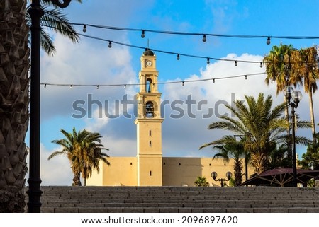 Bell tower of catholic cathedral. The wide stone erased steps of the ancient city. Sunset. Old Yaffo - one of the most ancient cities of the world. Concept active, informative and photo of tourism