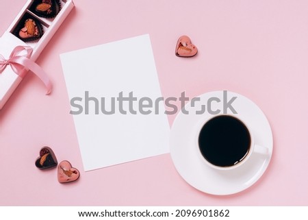 Chocolate candies hearts festive box, cup of coffee, blank sheet of paper pink background. Concept Valentine's Day