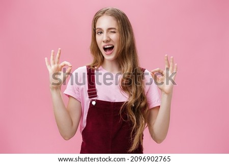 Waist-up shot of assertive good-looking confident teenage girl having everything under control winking delighted and self-assured showing okay gesture confirming job done well over pink background