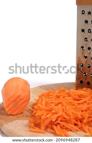 Shredding grater and shredded carrots on a cutting board