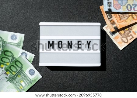 Lightbox board with the word MONEY in black letters around Euro banknotes. Finance background. Business, financial success and making money concept. Business budget of wealth and prosperity finance.