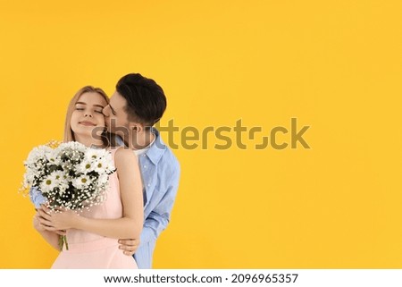 Cute couple with bouquet on yellow background