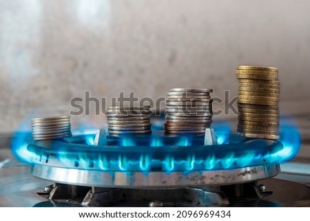Coins pile up on a burning gas burner. The concept is to increase the cost of supply , payment for natural gas. Royalty-Free Stock Photo #2096969434