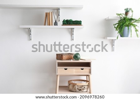 Stand-up table with decorative moss and basket near light wall