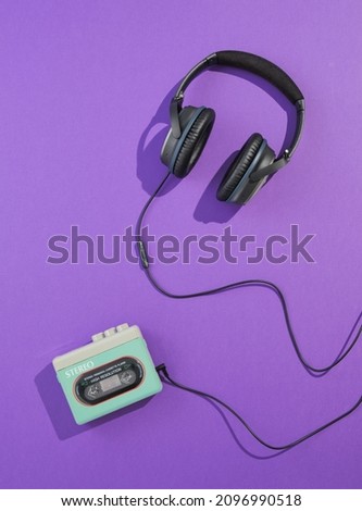 Flat lay composition with cassette player and headphones on purple background. Minimalist retro style and 80s music. Royalty-Free Stock Photo #2096990518