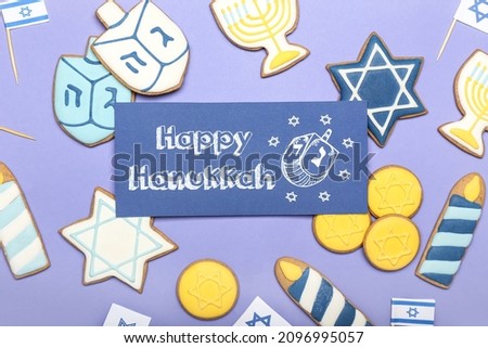 Tasty cookies and greeting card for Hanukkah on color background