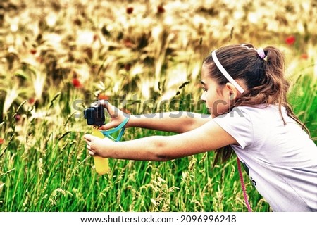 Young girl taking pictures of a wheat field in spring season with his action camera