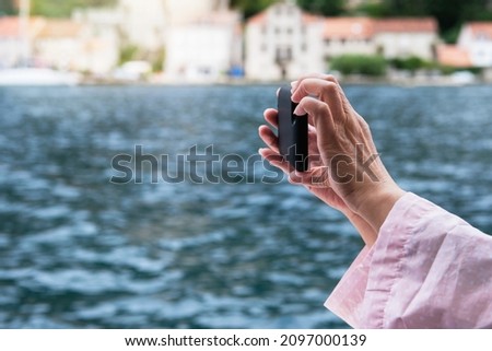 Woman hands holding mobile phone. Taking picture of nature by smartphone.