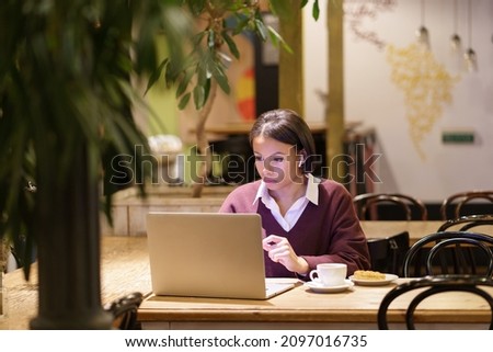 Young african american businesswoman working remotely in cafe, concentrated female journalist or editor writing article on laptop, black woman watching business webinar, sitting at coffeeshop table