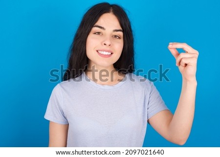 Caucasian woman wearing blue T-shirt over blue background  pointing up with hand showing up seven fingers gesture in Chinese sign language QÄ«.