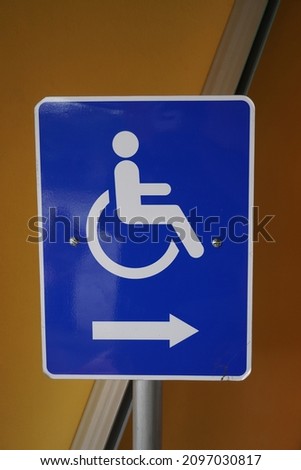This blue-based sign and a person using a wheelchair are used to provide information on the location of the lane facilities for people with disabilities.
