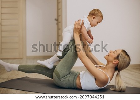 Mother practicing yoga with her baby daughter at home