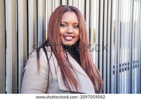 portrait of young african american woman standing on a wall. business woman with suit and long hair looking at camera.