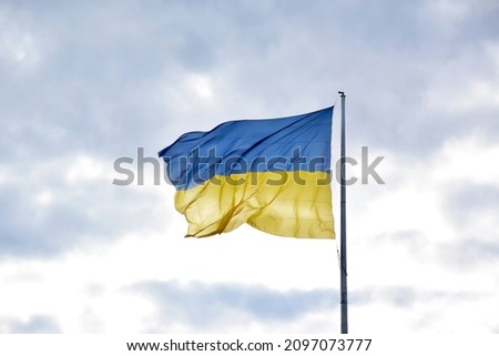 Large national flag of Ukraine flies in the blue sky. Big yellow blue Ukrainian state banner in the Kharkiv city. Independence, flag, Constitution Day, National Holiday, text space. Royalty-Free Stock Photo #2097073777