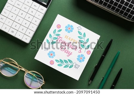 Happy Teacher's Day. Greeting card and office supplies on dark green background, top view