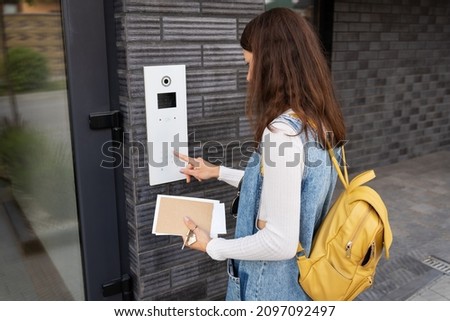 Rivne, Ukraine - 25 June, 2021: Door access control - a young woman student, holding a mail in her hands, enters the code to open the door. Door code Royalty-Free Stock Photo #2097092497