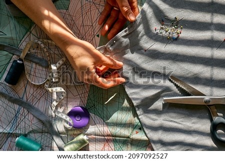 Woman is sketching pattern on a linen fabric Seamstress basting and sewing in a small studio Sartorial clothes Fashion studio, tailoring, handmade clothing concept Slow fashion Conscious consumption