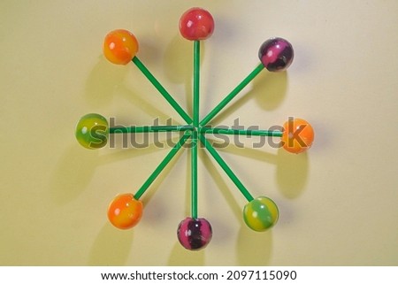 Colorful lollipops on green sticks in round. Multicolored candies on pastel background, top view. Summer and pop art concept. Flat lay. Real reflection