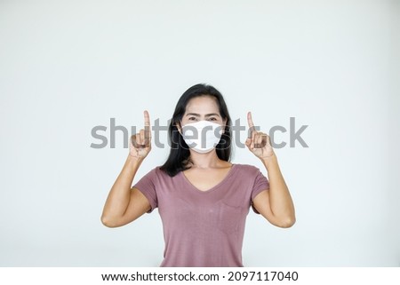 Portrait Asian woman wearing a face mask poses, pointing advertisement on white background, blank copy space with isolated cutout.