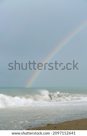 Beautiful seascape off the coast with rainbows, seagulls during storm waves. Vertical photo