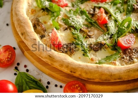 Appetizing, fresh pizza is on the table. Food from an Italian restaurant. Cooking pizza. Pizza ingredients. Dinner with friends.
