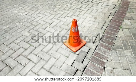 A traffic cone on paving block in parking area