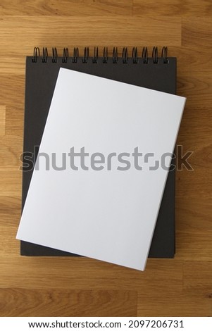 White paper, sketchbooks, black albums on wooden background