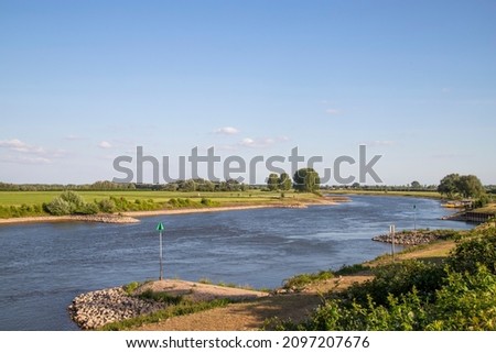 The Dutch river IJssel flows peacefully through the typical Dutch landscape. Royalty-Free Stock Photo #2097207676